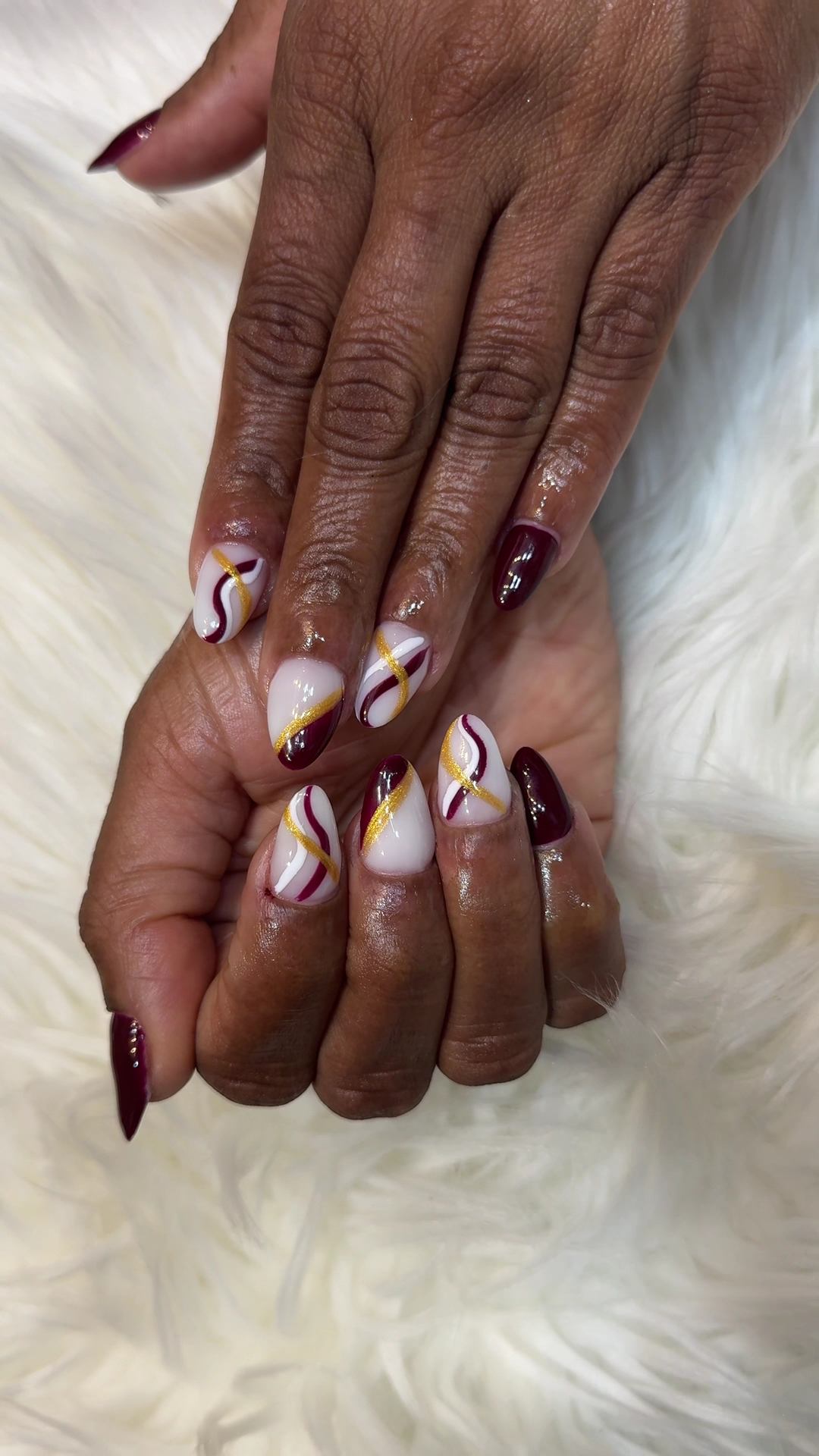 Nail art with swirls and burgundy accents