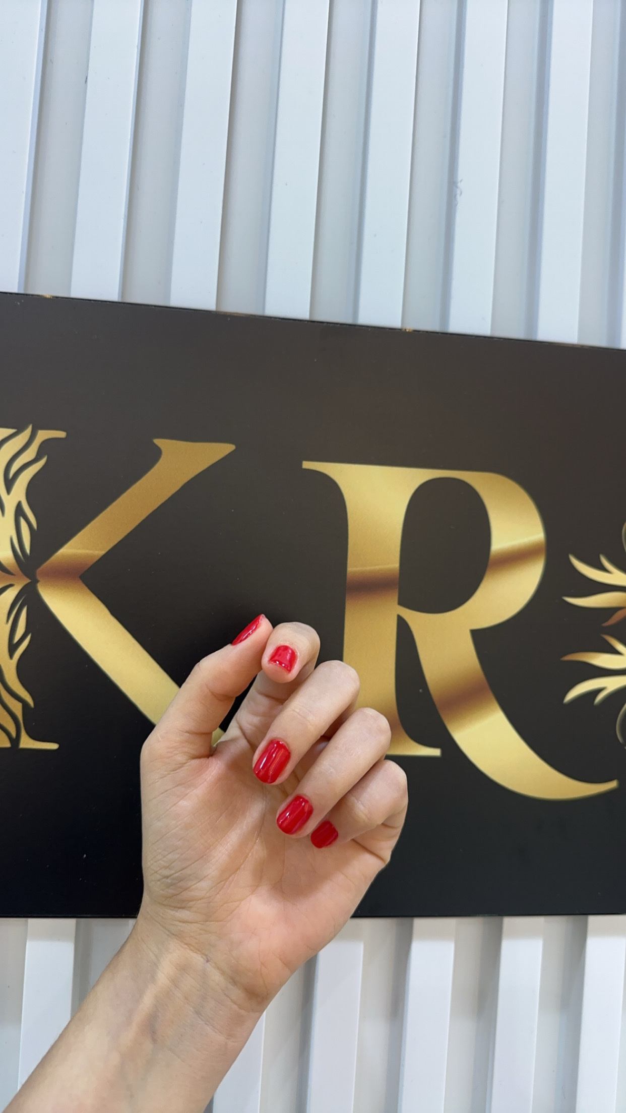 Red gel manicure in front of the gold KRG sign